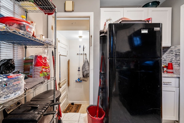 kitchen with backsplash, white cabinetry, and black refrigerator