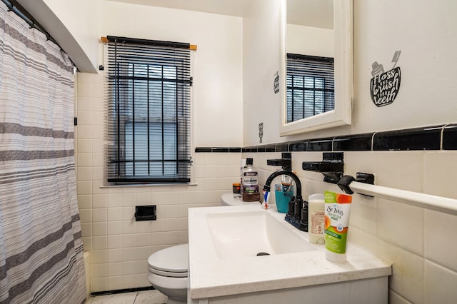 bathroom with vanity, toilet, and tile walls