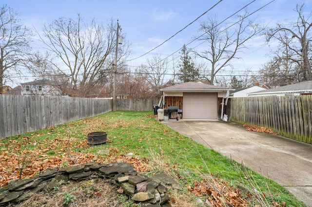 view of yard featuring a garage, an outdoor fire pit, and an outdoor structure