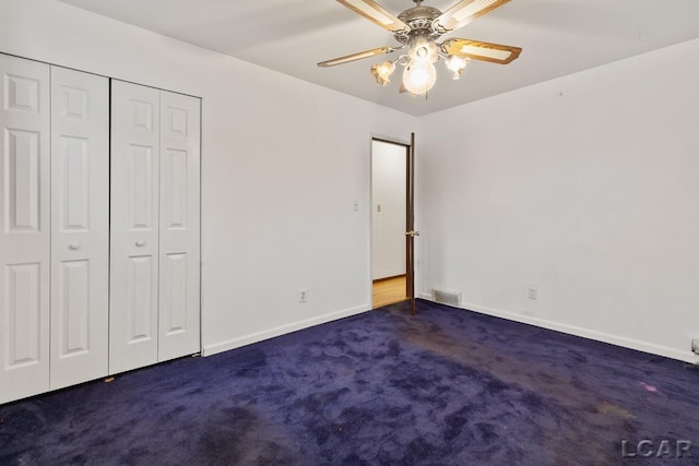 unfurnished bedroom with dark colored carpet, a closet, and ceiling fan