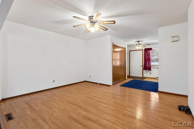 empty room featuring ceiling fan, a textured ceiling, and light hardwood / wood-style flooring