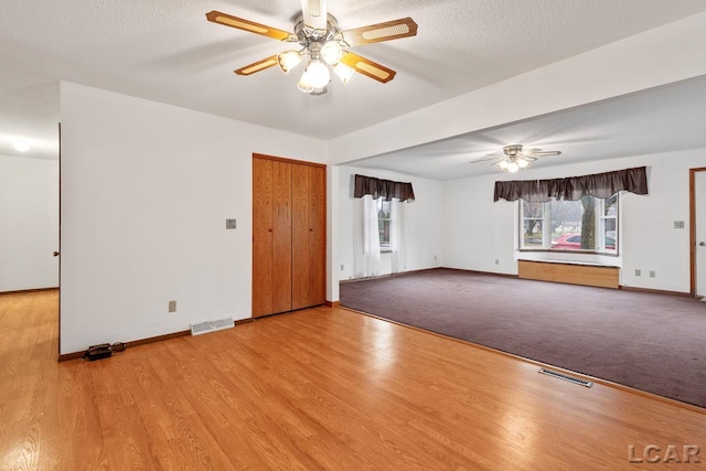 spare room featuring plenty of natural light, a textured ceiling, and light hardwood / wood-style flooring