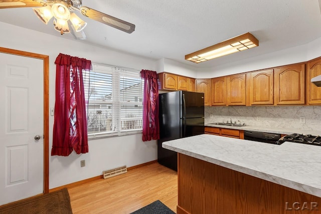 kitchen with ceiling fan, sink, backsplash, black appliances, and light wood-type flooring