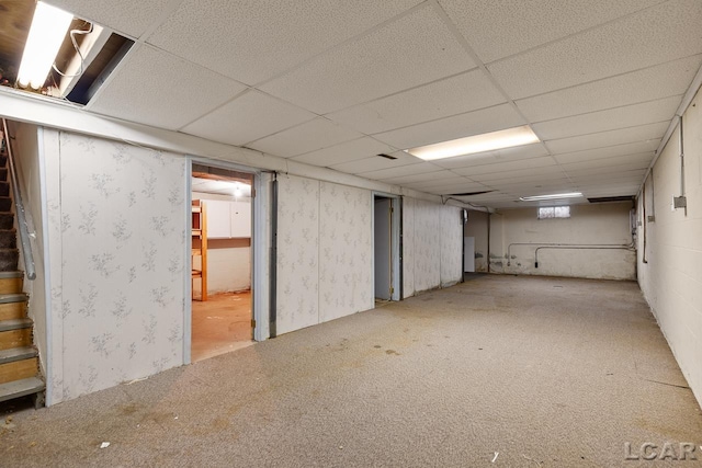 basement with a drop ceiling and light carpet