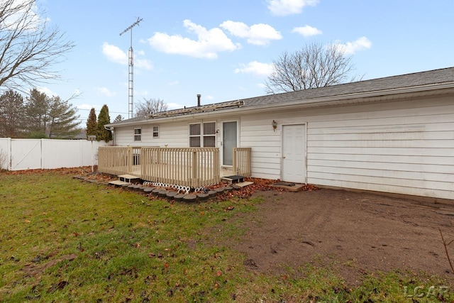 back of property with a deck and a yard