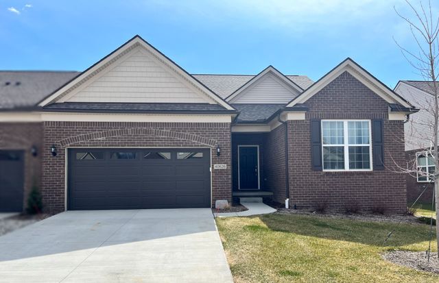 view of front of home featuring brick siding, an attached garage, driveway, and a front lawn