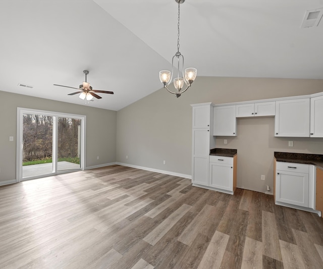 kitchen with white cabinets, ceiling fan with notable chandelier, lofted ceiling, and light hardwood / wood-style flooring