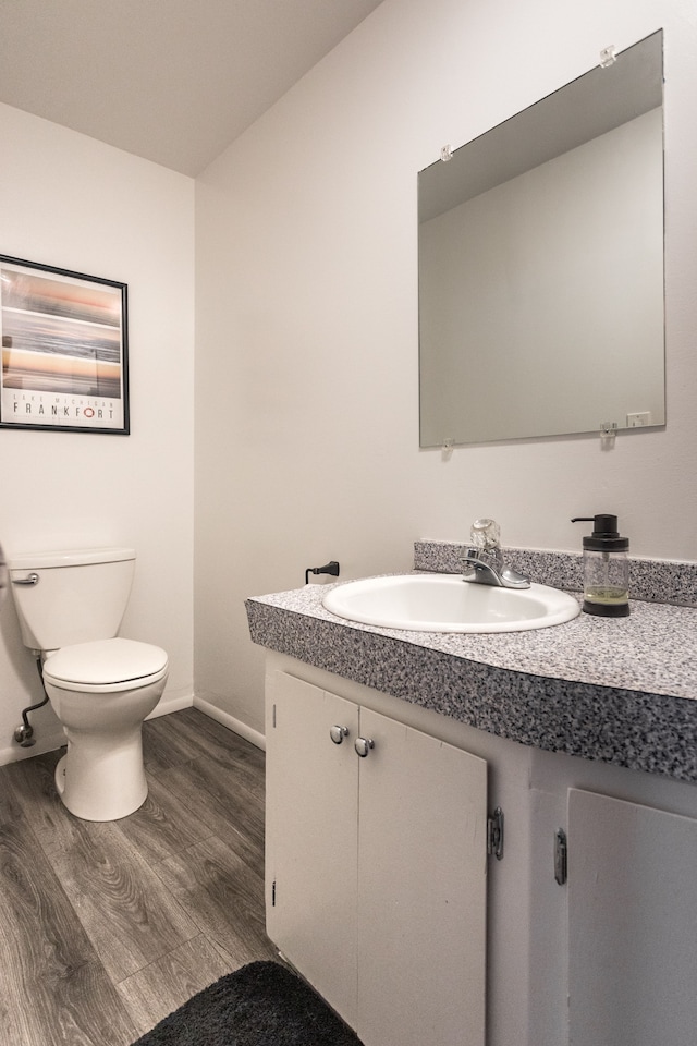 bathroom with hardwood / wood-style floors, vanity, and toilet