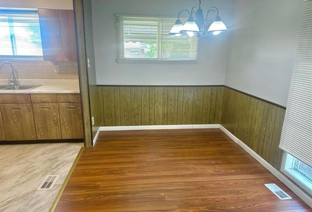 unfurnished dining area featuring light wood-type flooring, sink, and a chandelier