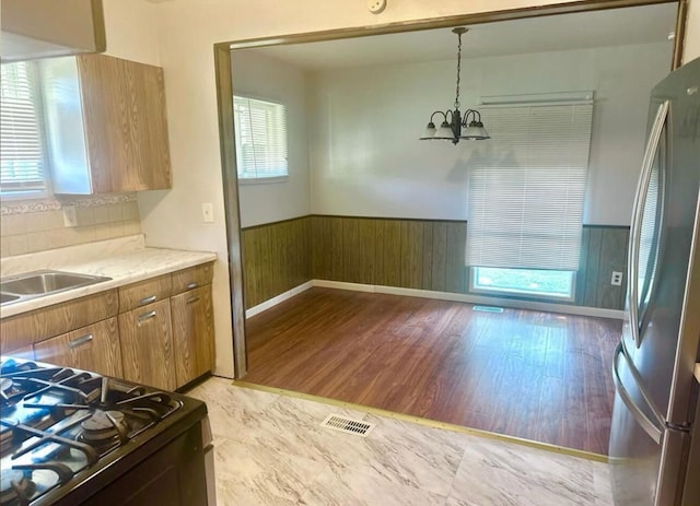 kitchen featuring stove, an inviting chandelier, sink, hanging light fixtures, and stainless steel fridge