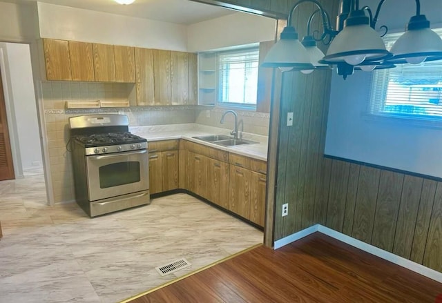 kitchen featuring light wood-type flooring, tasteful backsplash, stainless steel gas range oven, and sink