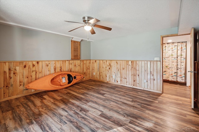 spare room featuring wood-type flooring, a textured ceiling, ceiling fan, and wood walls