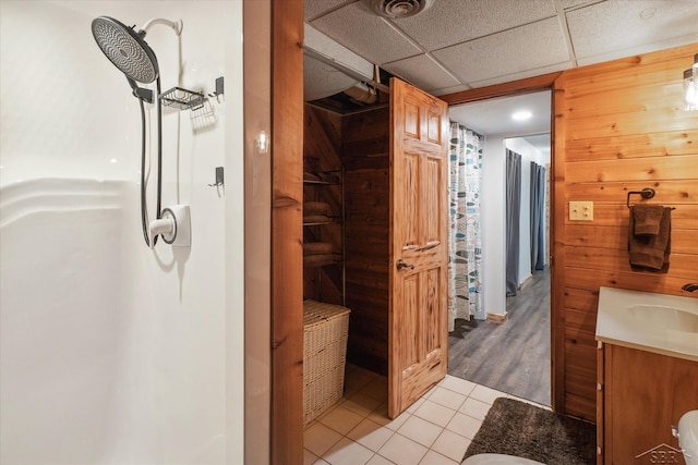 bathroom with wood-type flooring, vanity, a paneled ceiling, and wooden walls