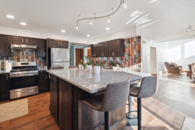 kitchen featuring a breakfast bar, tasteful backsplash, a kitchen island, dark hardwood / wood-style flooring, and stainless steel appliances