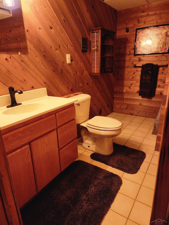 bathroom with tile patterned floors, vanity, a wood stove, toilet, and wood walls