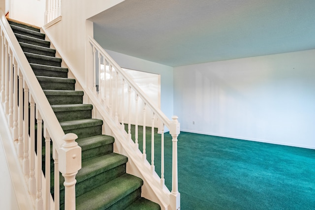 stairway with carpet and a textured ceiling