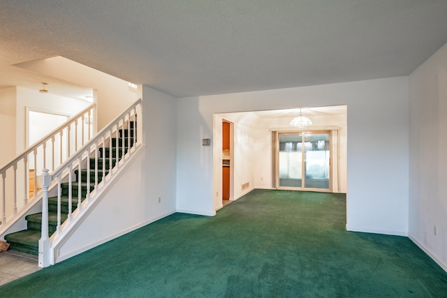 carpeted spare room with a chandelier and a textured ceiling