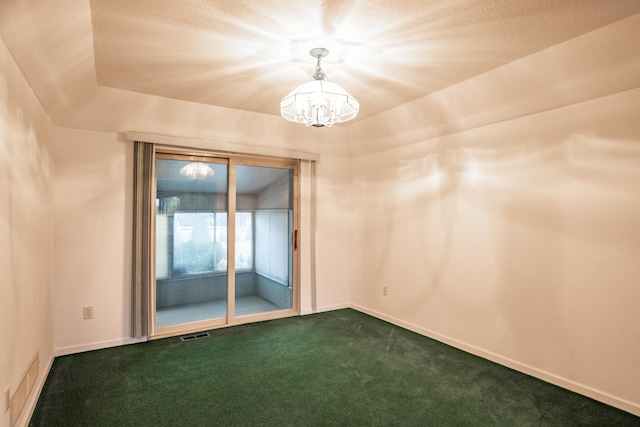 carpeted spare room featuring a notable chandelier, a raised ceiling, and a textured ceiling