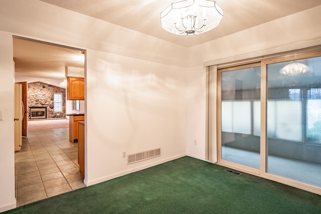 spare room featuring a notable chandelier, a stone fireplace, lofted ceiling, and light carpet