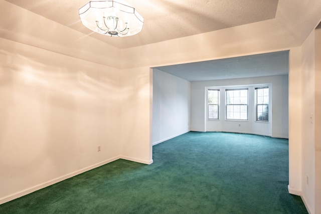 carpeted spare room with a raised ceiling, a textured ceiling, and an inviting chandelier