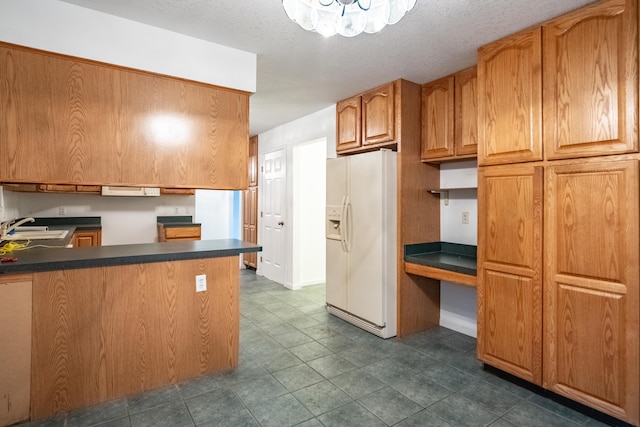 kitchen with white fridge with ice dispenser, sink, dark tile patterned floors, kitchen peninsula, and a textured ceiling