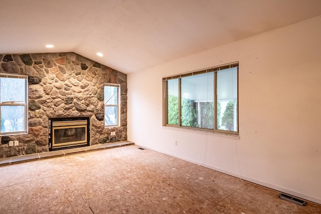 unfurnished living room with a stone fireplace and vaulted ceiling