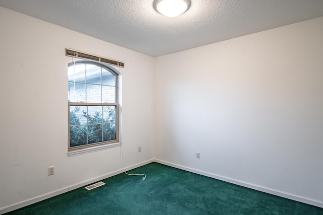 spare room with dark carpet and a textured ceiling