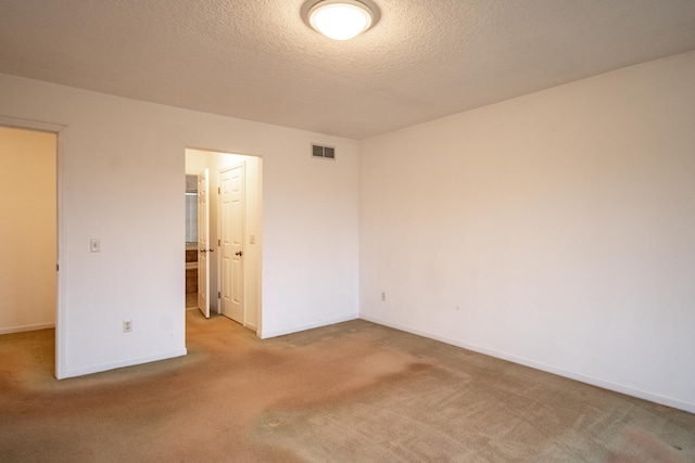 unfurnished bedroom with a spacious closet, light colored carpet, and a textured ceiling