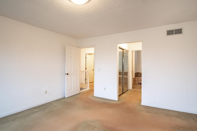 unfurnished bedroom with a closet, light colored carpet, and a textured ceiling