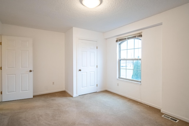 unfurnished bedroom with a textured ceiling and light colored carpet