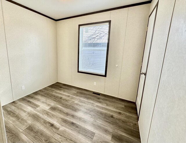 empty room with light hardwood / wood-style floors and ornamental molding