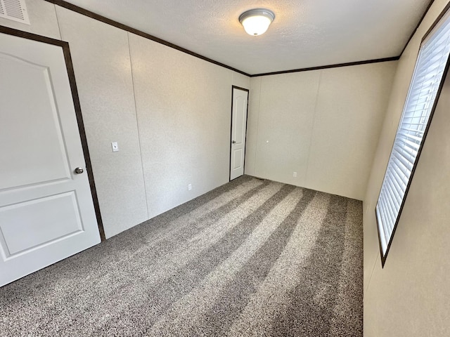 unfurnished bedroom with carpet floors, a textured ceiling, and ornamental molding