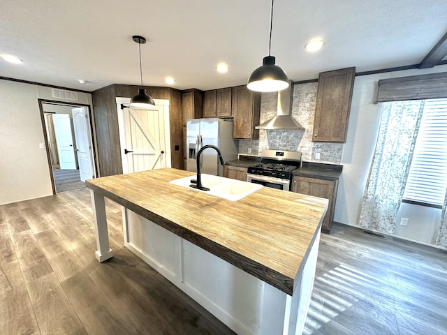 kitchen with sink, stainless steel appliances, wooden counters, wood-type flooring, and a center island with sink