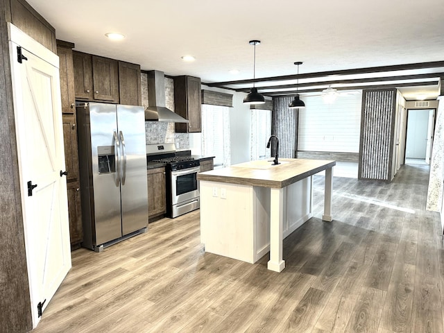 kitchen with wall chimney exhaust hood, light wood-type flooring, stainless steel appliances, and decorative light fixtures