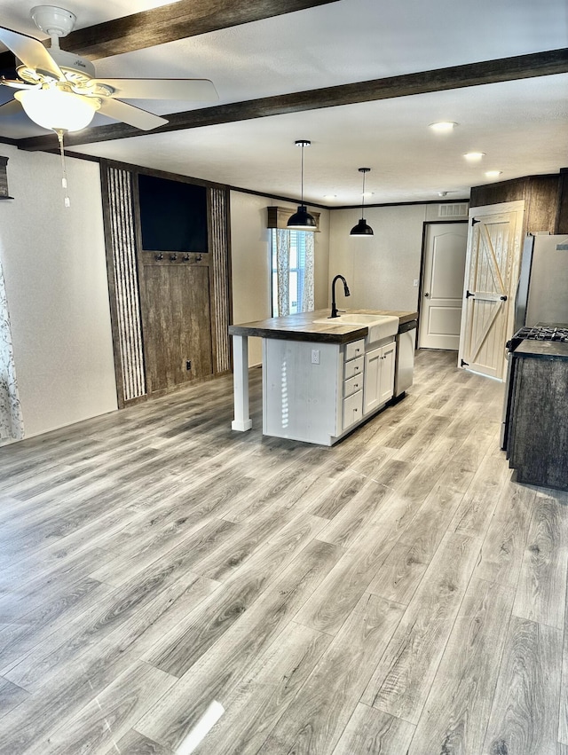 kitchen featuring a kitchen island with sink, light hardwood / wood-style flooring, ceiling fan, a barn door, and appliances with stainless steel finishes