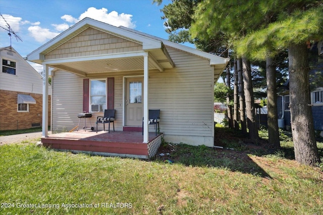 rear view of property featuring covered porch, cooling unit, a wooden deck, and a lawn