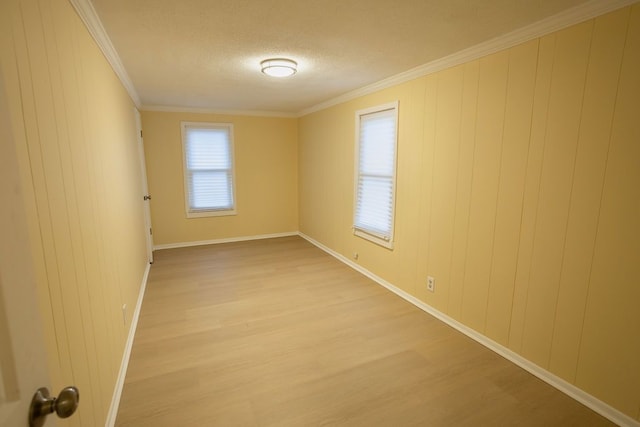 unfurnished room featuring crown molding, light hardwood / wood-style flooring, and wood walls