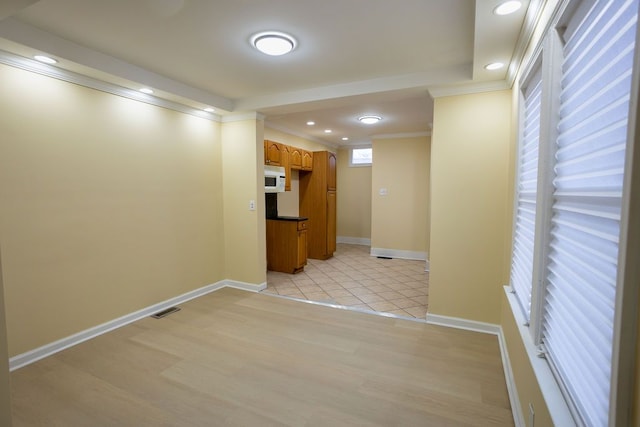 hallway with light hardwood / wood-style flooring and ornamental molding