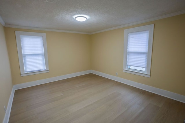 empty room with crown molding, plenty of natural light, a textured ceiling, and light wood-type flooring