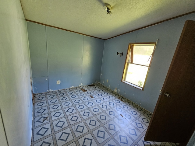 spare room featuring vaulted ceiling, a textured ceiling, and ornamental molding