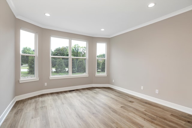 empty room with crown molding, a healthy amount of sunlight, and light wood-type flooring