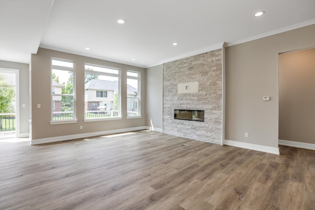 unfurnished living room with ornamental molding, light hardwood / wood-style flooring, and a stone fireplace