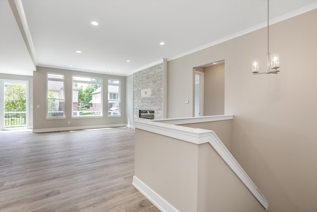 unfurnished living room featuring light wood-type flooring, heating unit, crown molding, a notable chandelier, and a fireplace