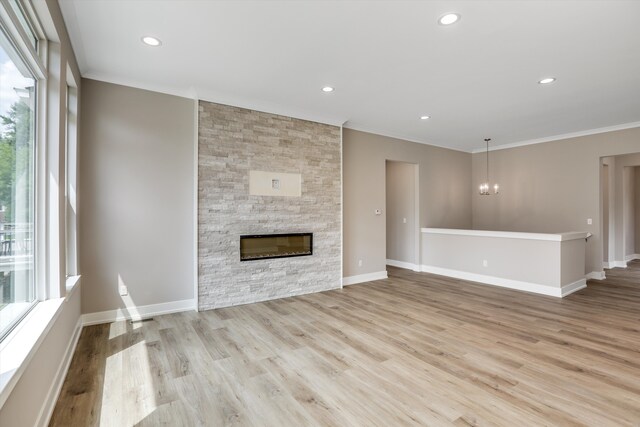 unfurnished living room featuring a fireplace, light hardwood / wood-style floors, plenty of natural light, and crown molding