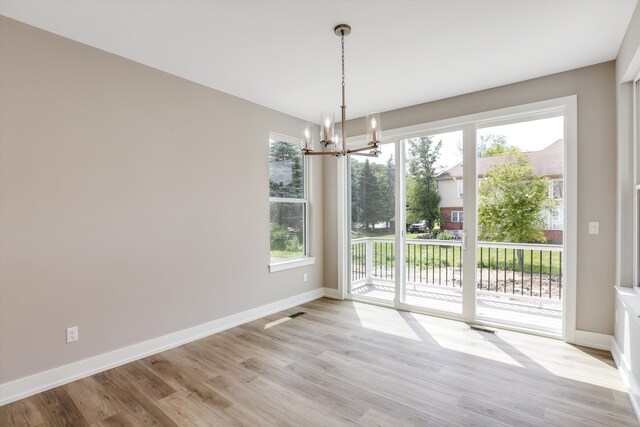 unfurnished dining area with a chandelier and light wood-type flooring