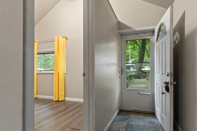 doorway to outside with light hardwood / wood-style flooring, vaulted ceiling, and a healthy amount of sunlight