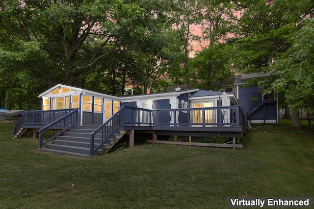 back house at dusk featuring a lawn and a deck