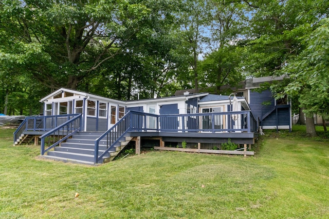 back of house featuring a sunroom, a deck, and a lawn