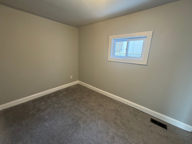 spare room featuring dark carpet