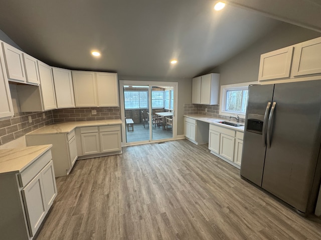 kitchen with stainless steel fridge with ice dispenser, tasteful backsplash, white cabinetry, and light hardwood / wood-style floors